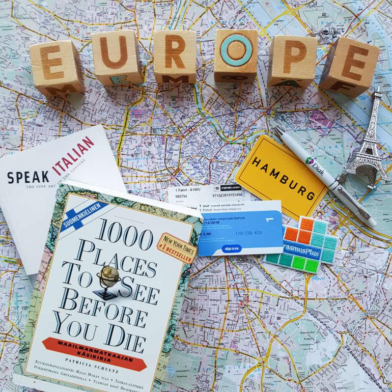 On top of a map small souvenirs from abroad and the text Europe written with play cubes.