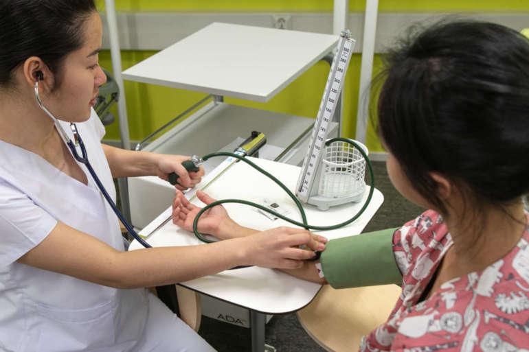 Opiskelija mittaa verenpainetta potilaalta.