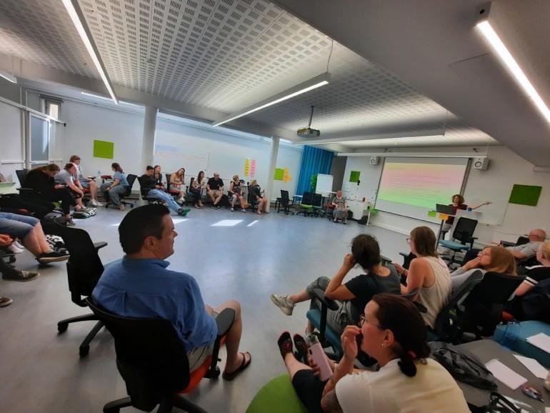 People in a lecture room in a circle.