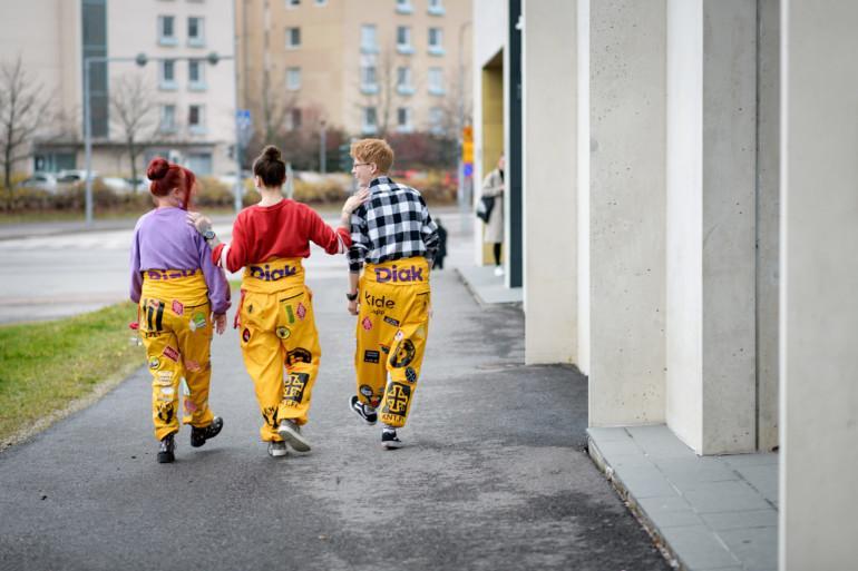 Kolme haalaripukuista opiskelijaa kävelee Helsingin-kampuksen rakennuksen vieressä.