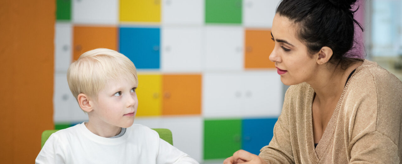 Nainen ja lapsi keskustelevat pöydän ääressä, kuvituskuva.