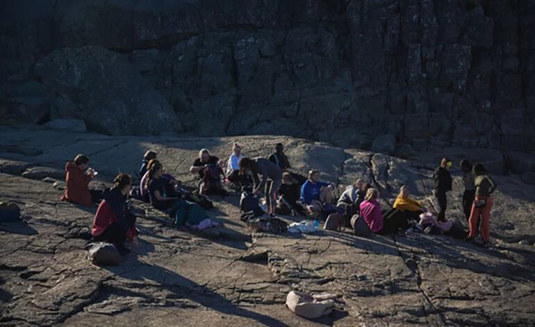 Opiskelijoita istumassa kalliolla.