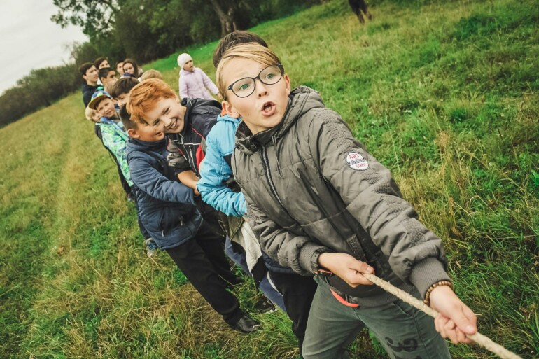 Kuvituskuva, lapset vetävät köyttä pellolla.