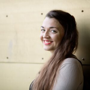 Nainen katsoo kameraan ja hymyilee.