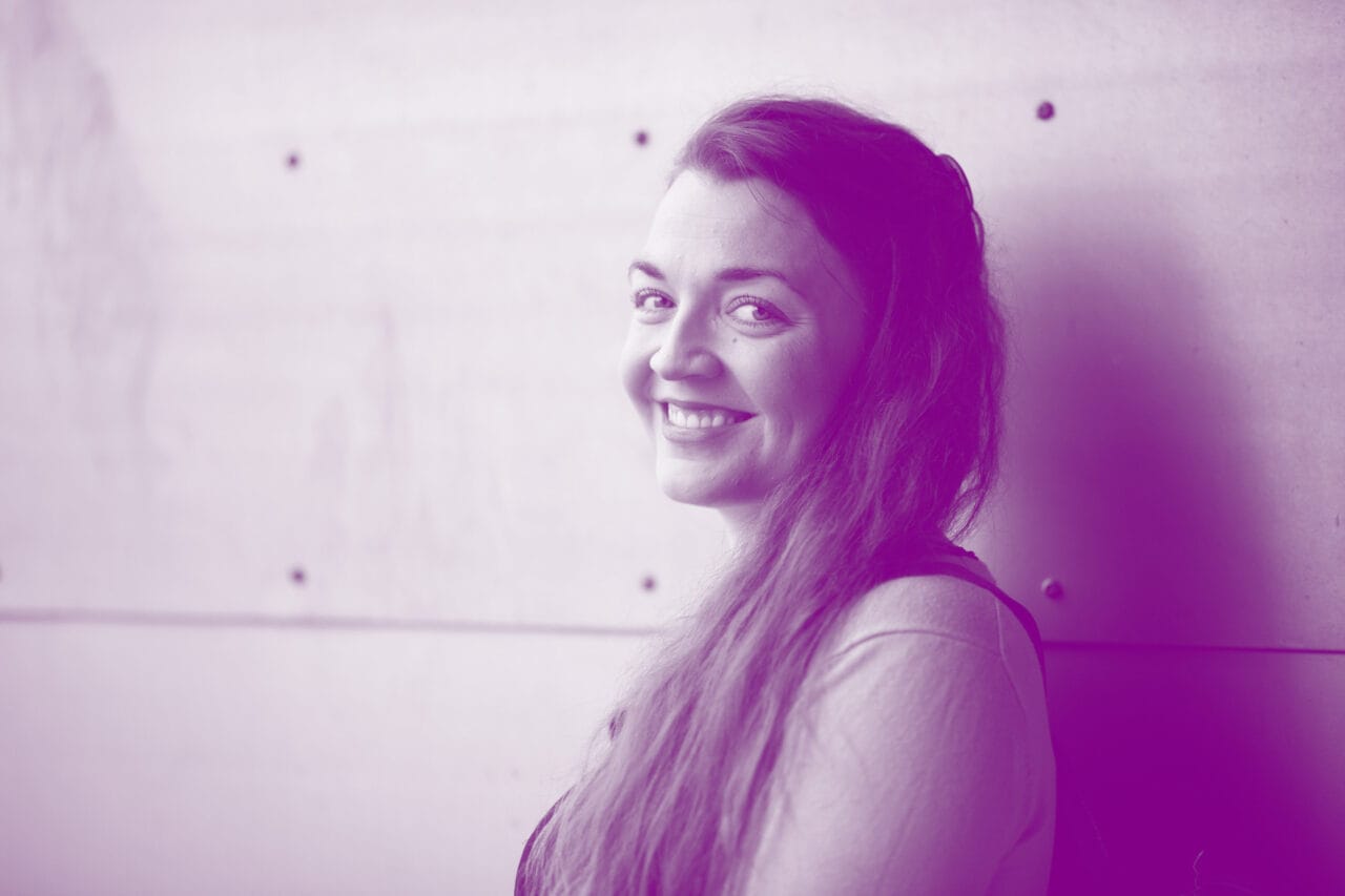 Nainen katsoo kohti hymyillen.