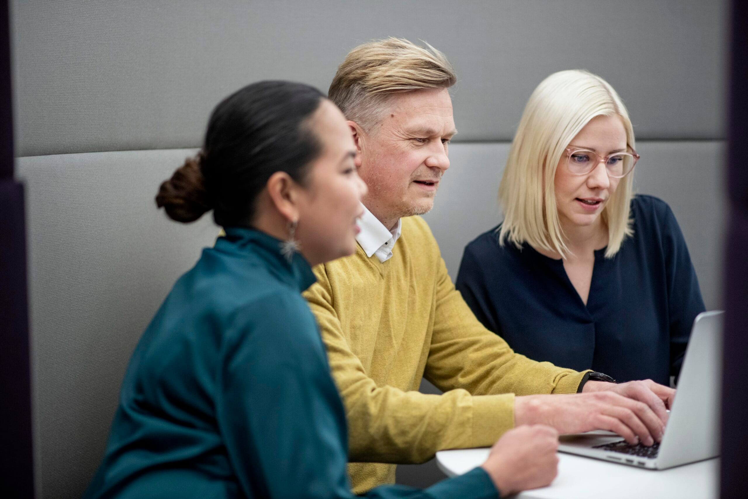 Kolme ihmistä vierekkäin tietokoneen ääressä, kuvituskuva.