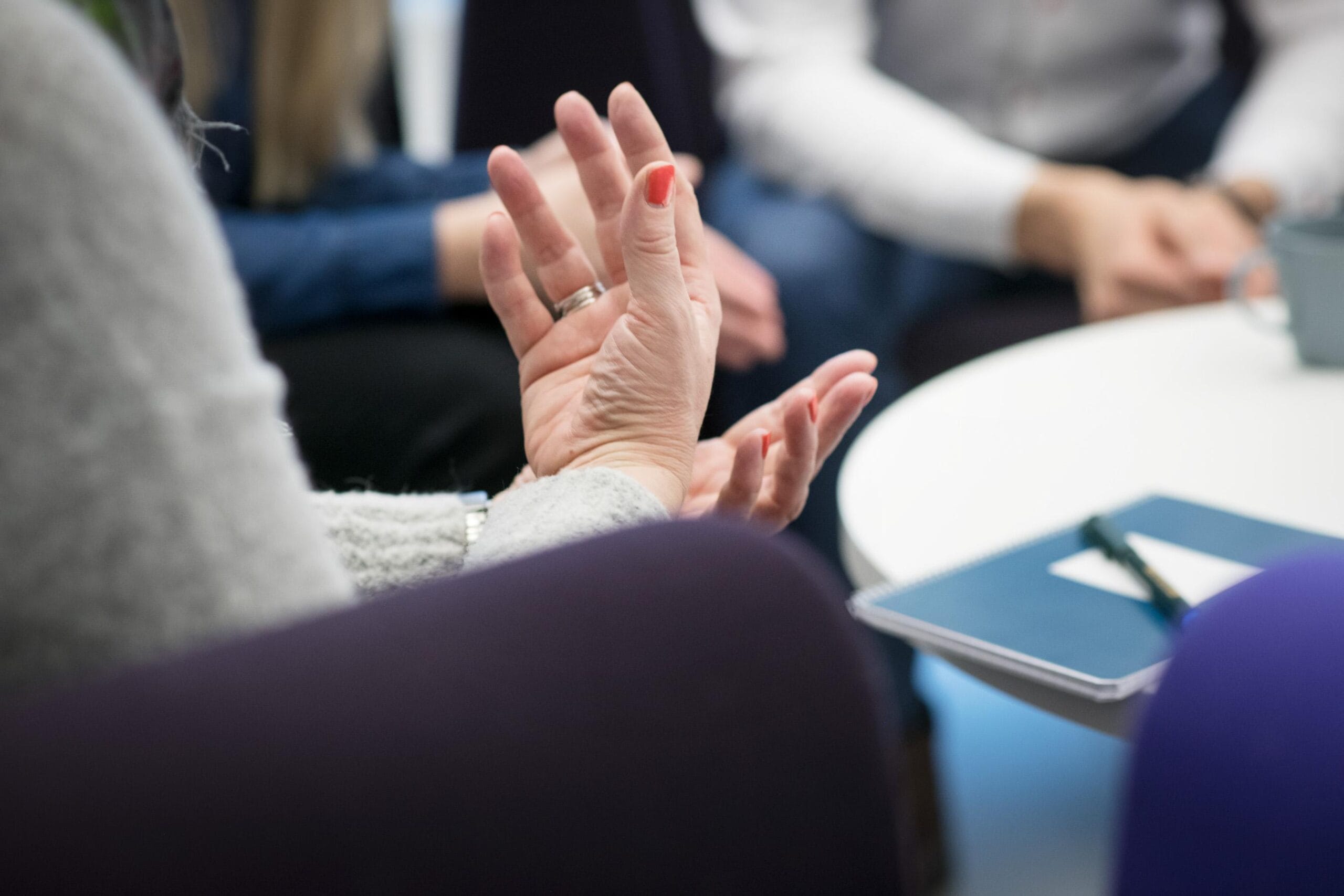 Kuva käsistä pöydän ääressä.