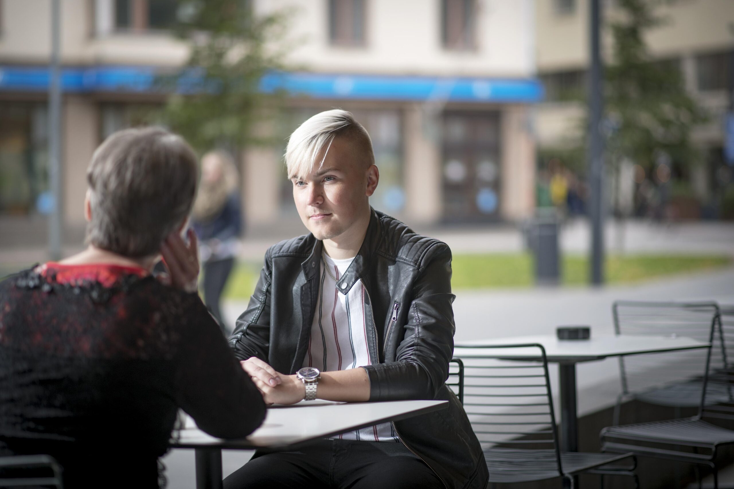 Nuori ja aikuinen juttelemassa pöydän ääressä, kuvituskuva.