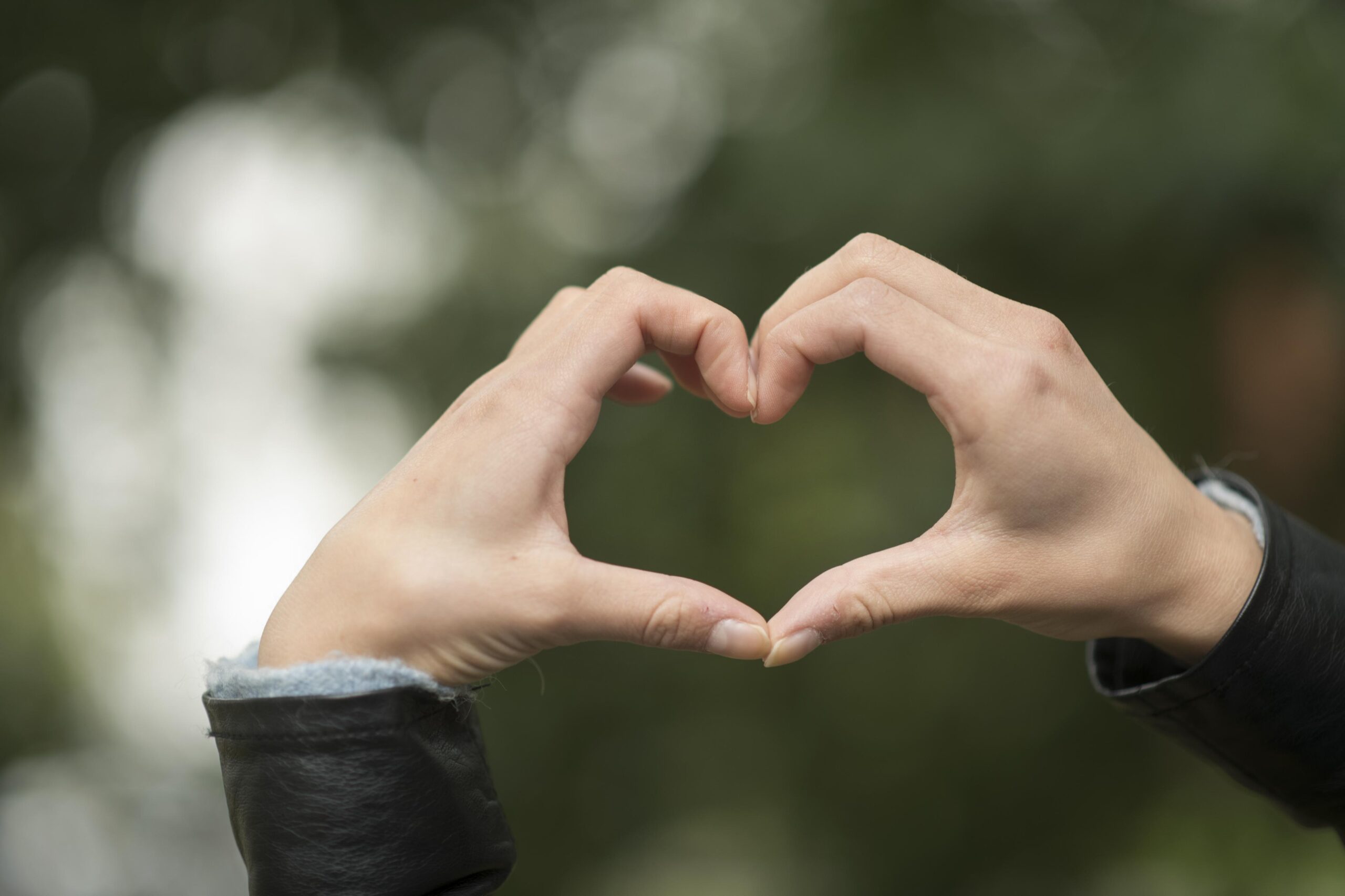 yksi taluttaa polkupyörää.kaksi henkilöä kahvilapöydän ääressä ulkona.naurava nainen katsoo selin olevaa naista.kädet muodostavat sydämen.