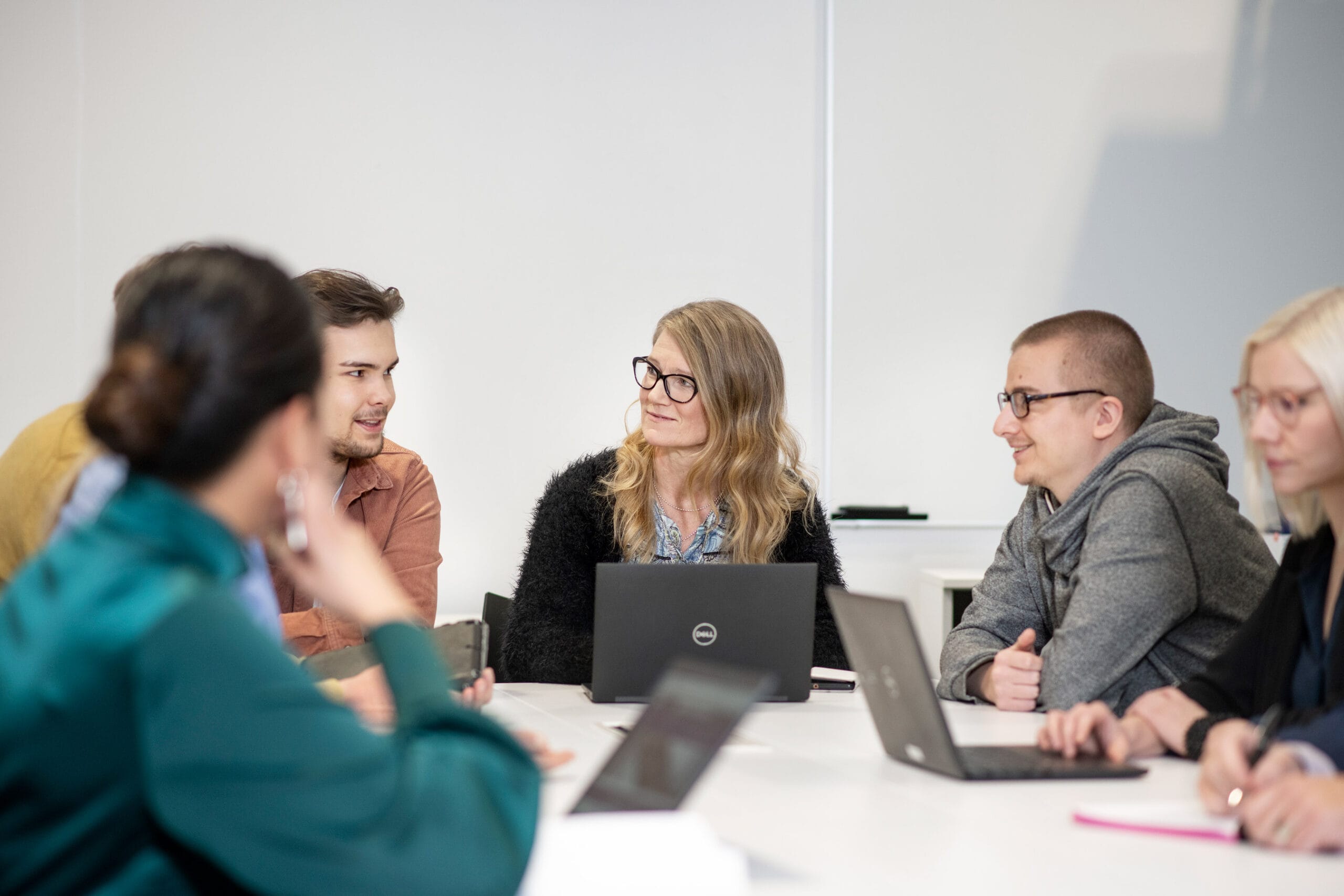 Ihmisiä pöydän ääressä istumassa, kuvituskuva.