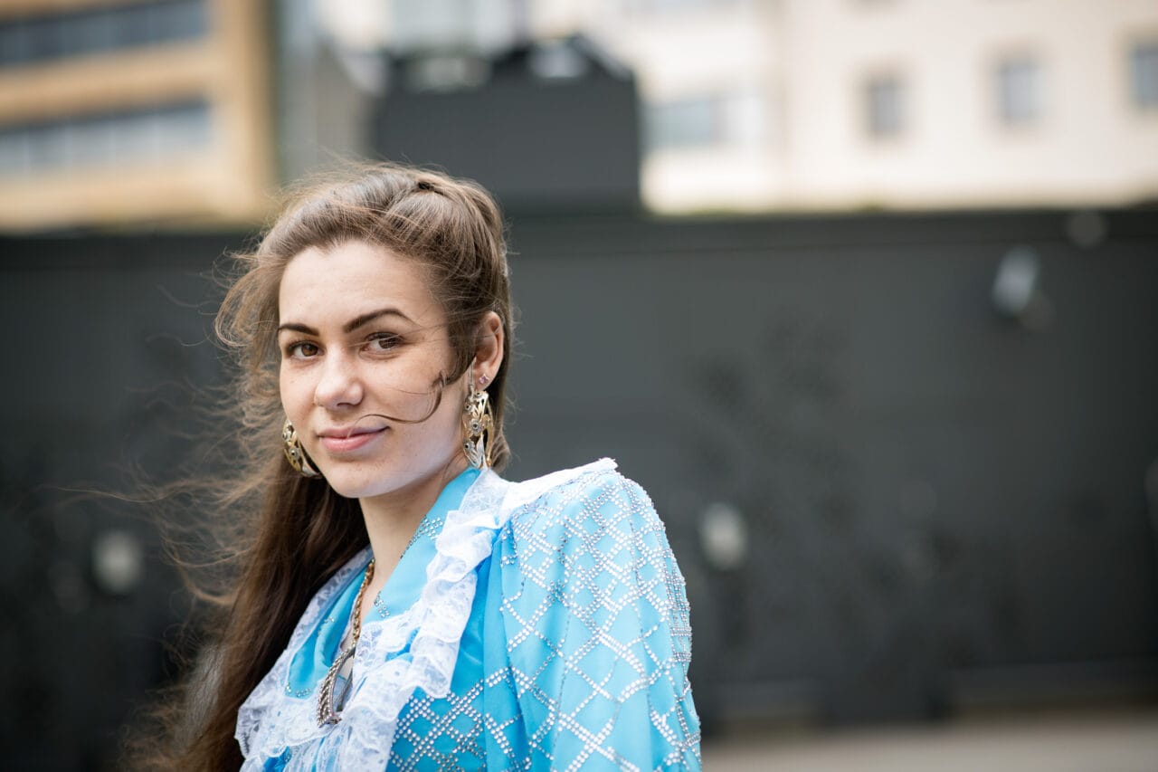 Kolme kättä päällekkäin yhteistyön merkkinä.Romaniasuinen nainen osoittaa valkotaululle kiinnitettyä suunnitelmapaperia kahdelle muulle henkilölle.Opiskelijoita istumassa pöydän ääressä.