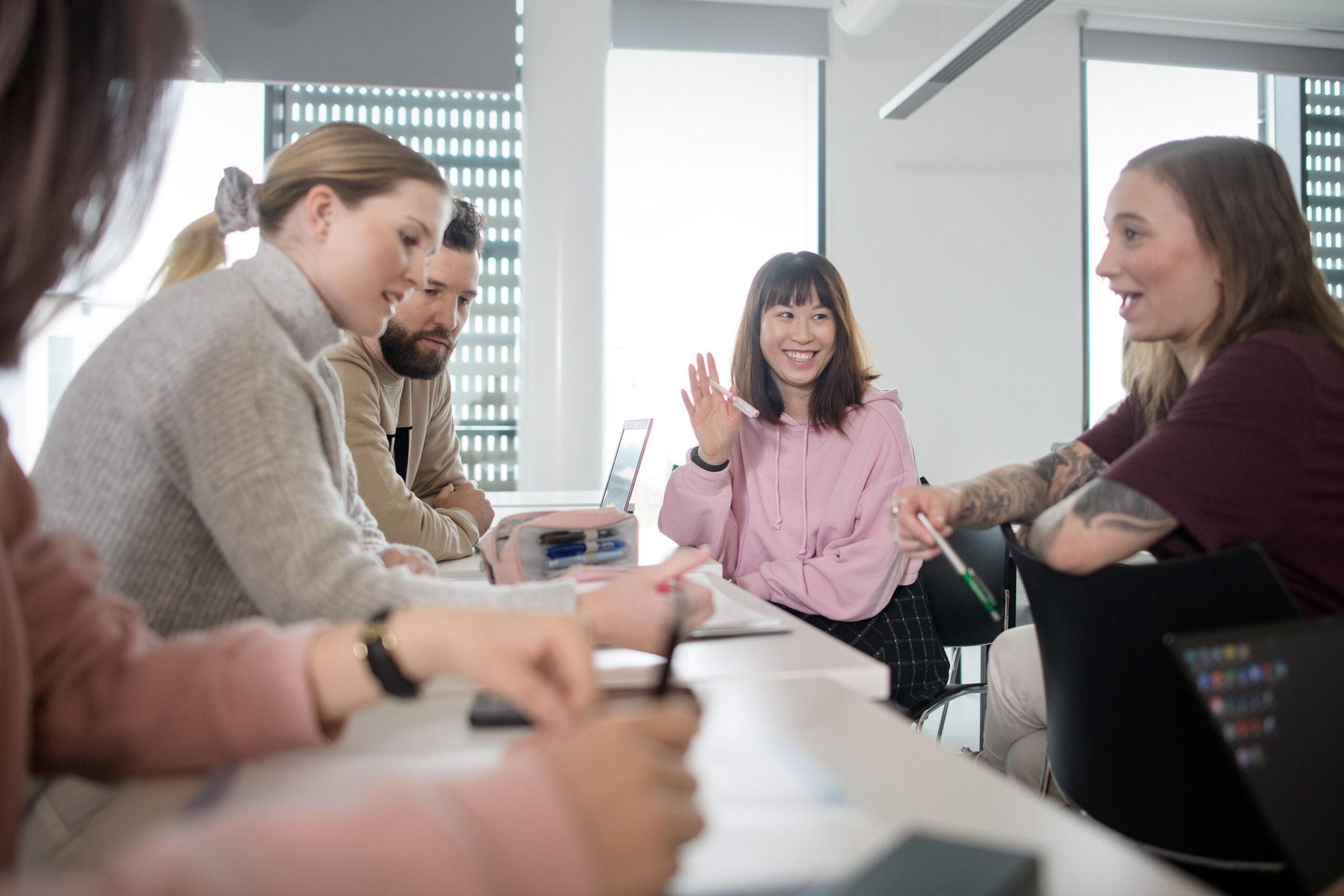 Opiskelijoita istumassa pöydän ääressä.