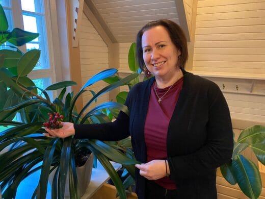 Diakin opiskelija hymyilee violetti paita päällään kampuksella.