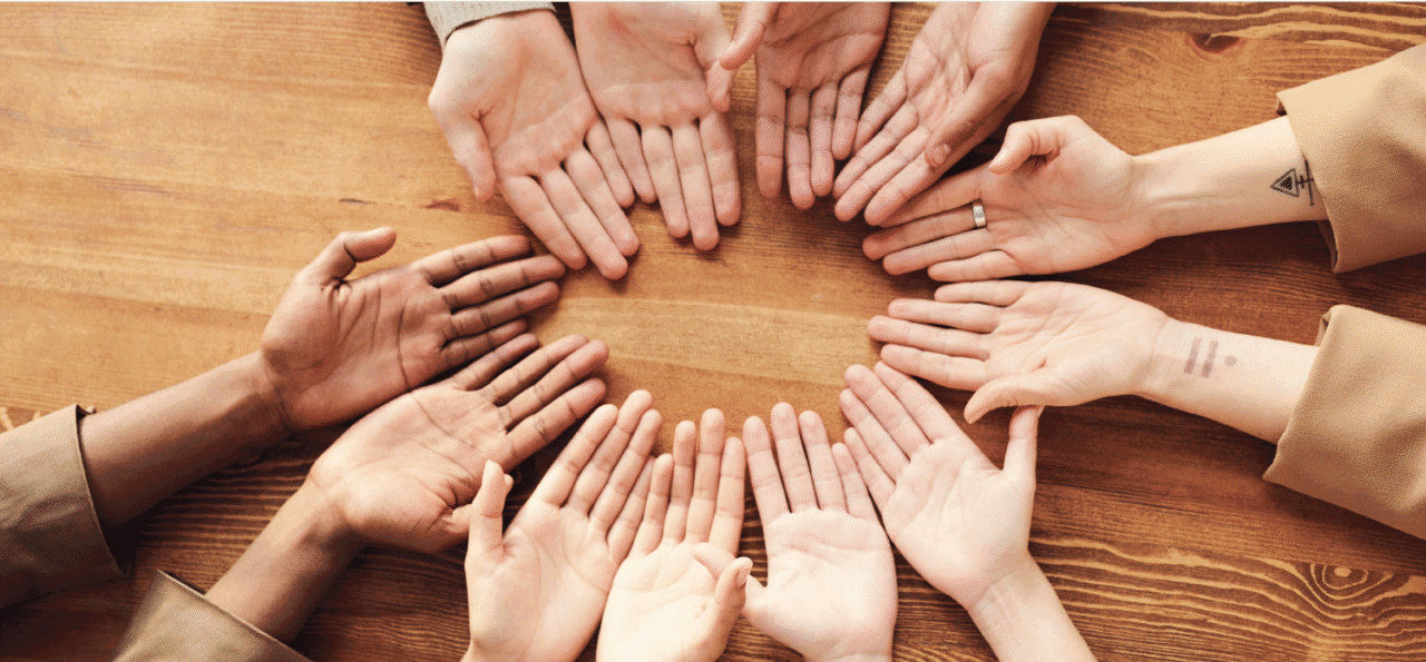 Kuusi käsiparia pöydällä ympyrässä, kämmenpuoli ylöspäin.