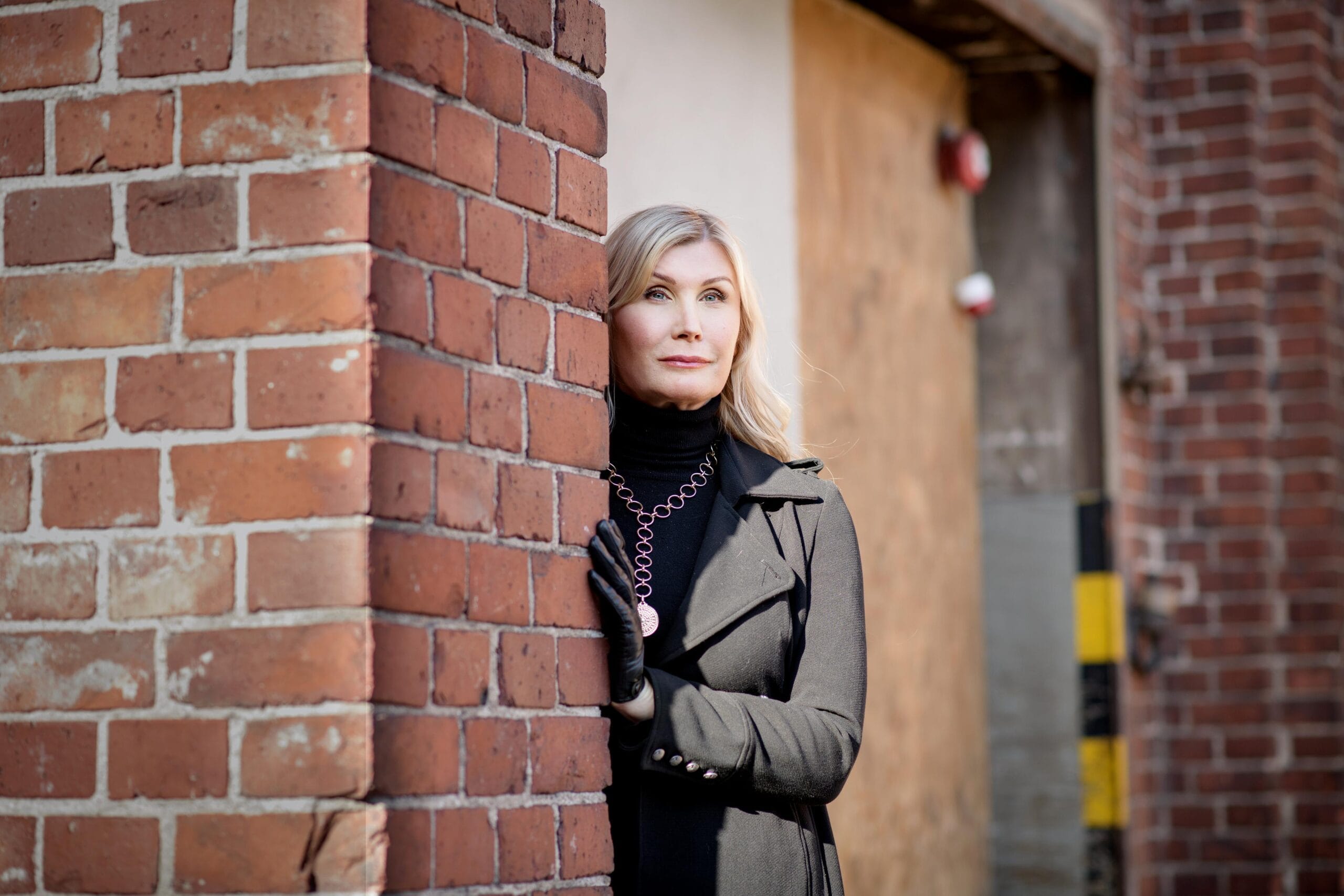 Julia Suikki nojaa tiiliseinään.