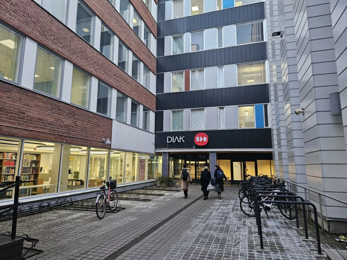 Diakin Oulun-kampus ulkoa päin: kerrostalorakennus, jonka edessä on ihmisiä.