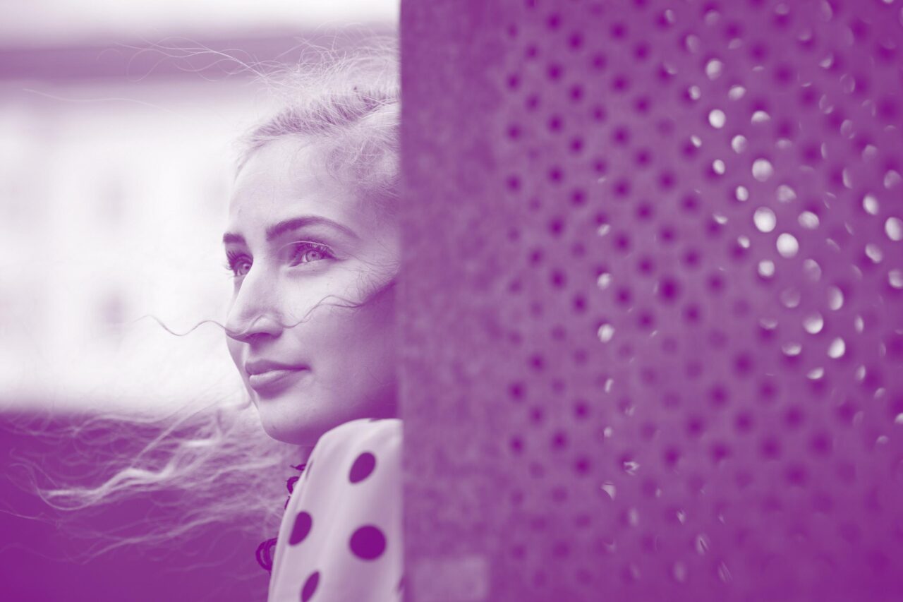 Nuori romaninainen kuvattuna sivulta. Etualalla seinä.