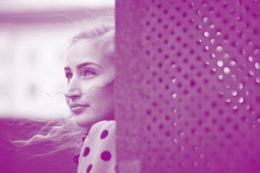 Nuori romaninainen kuvattuna sivulta. Etualalla seinä.