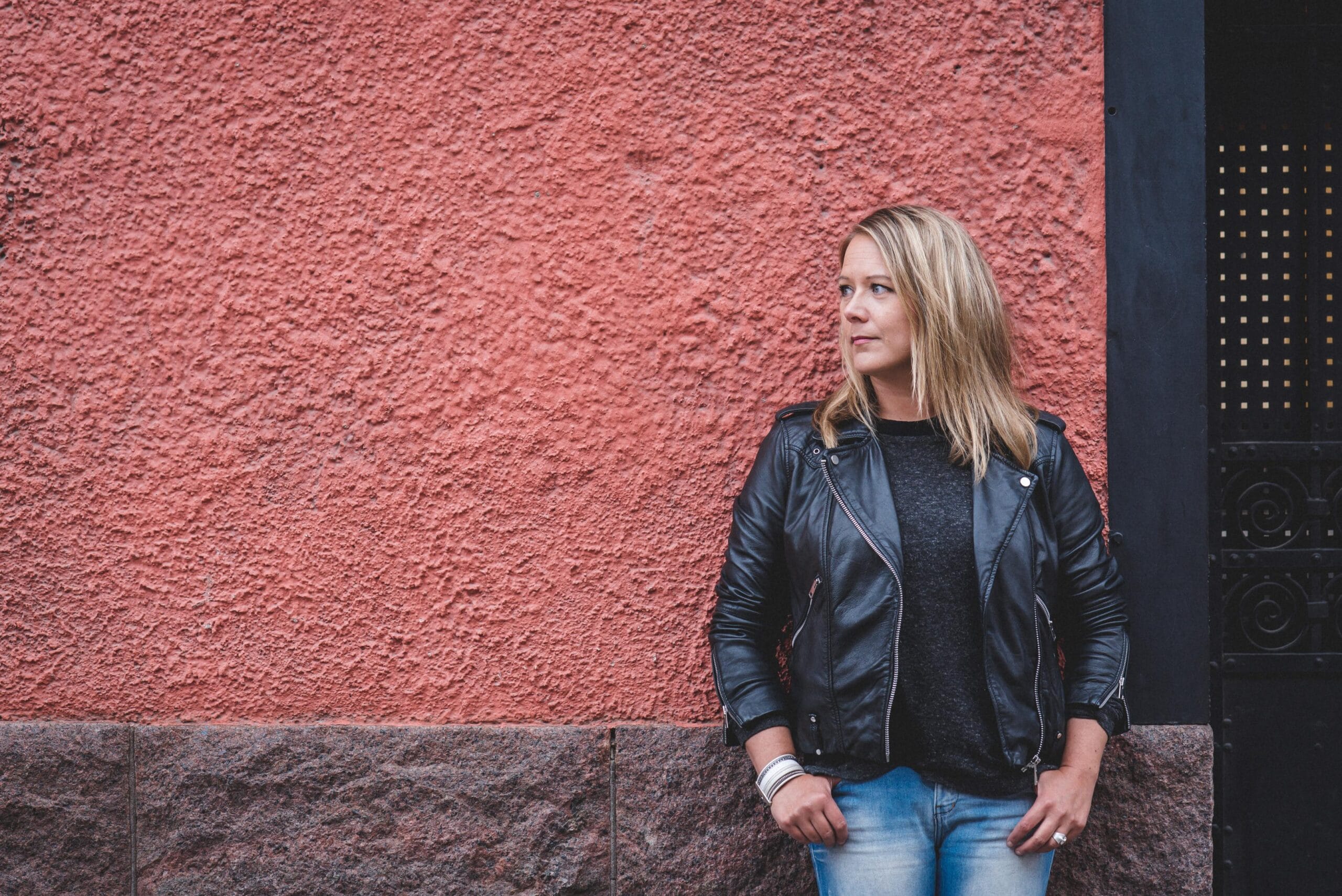 Satu Sutelainen nojaa rakennuksen seinää vasten.