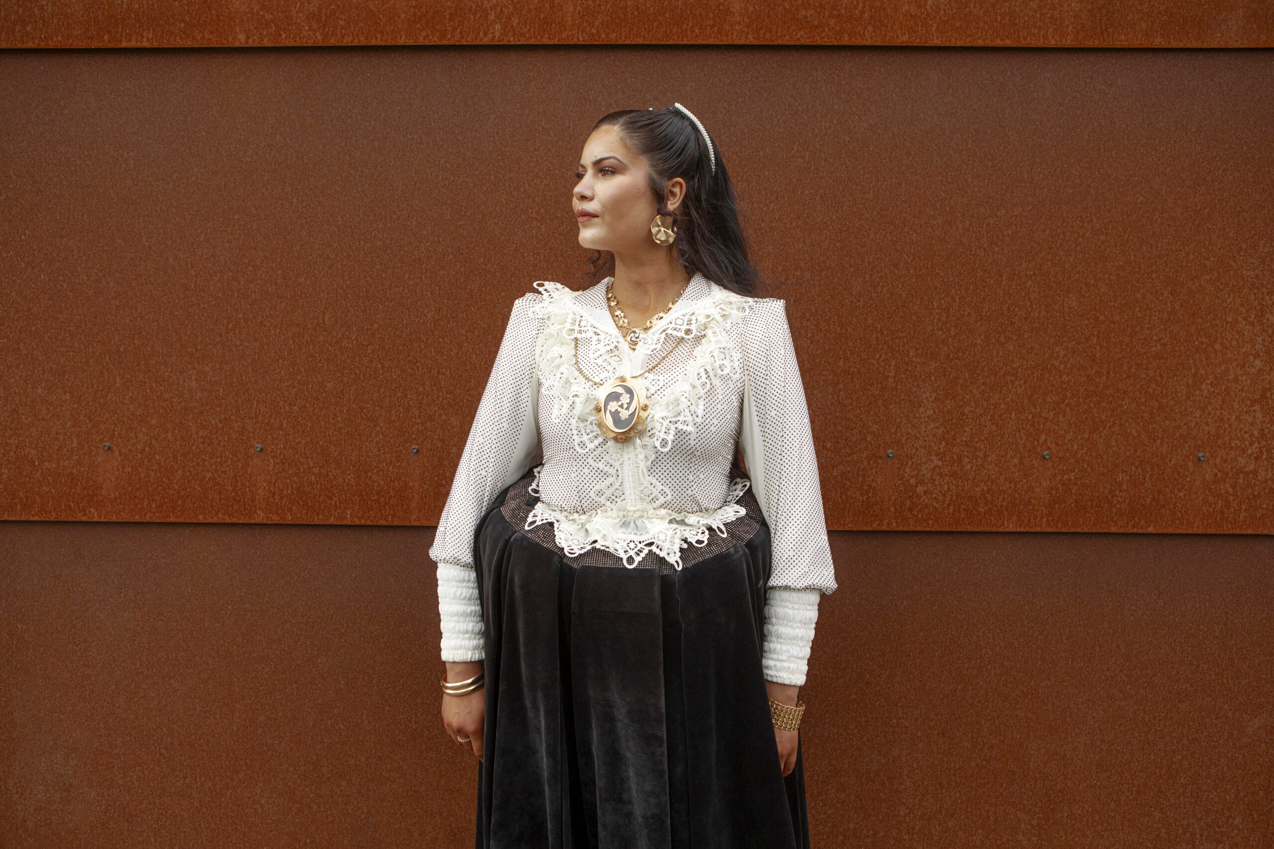 Nainen seisoo seinän edessä yllään romaninaisen puku.