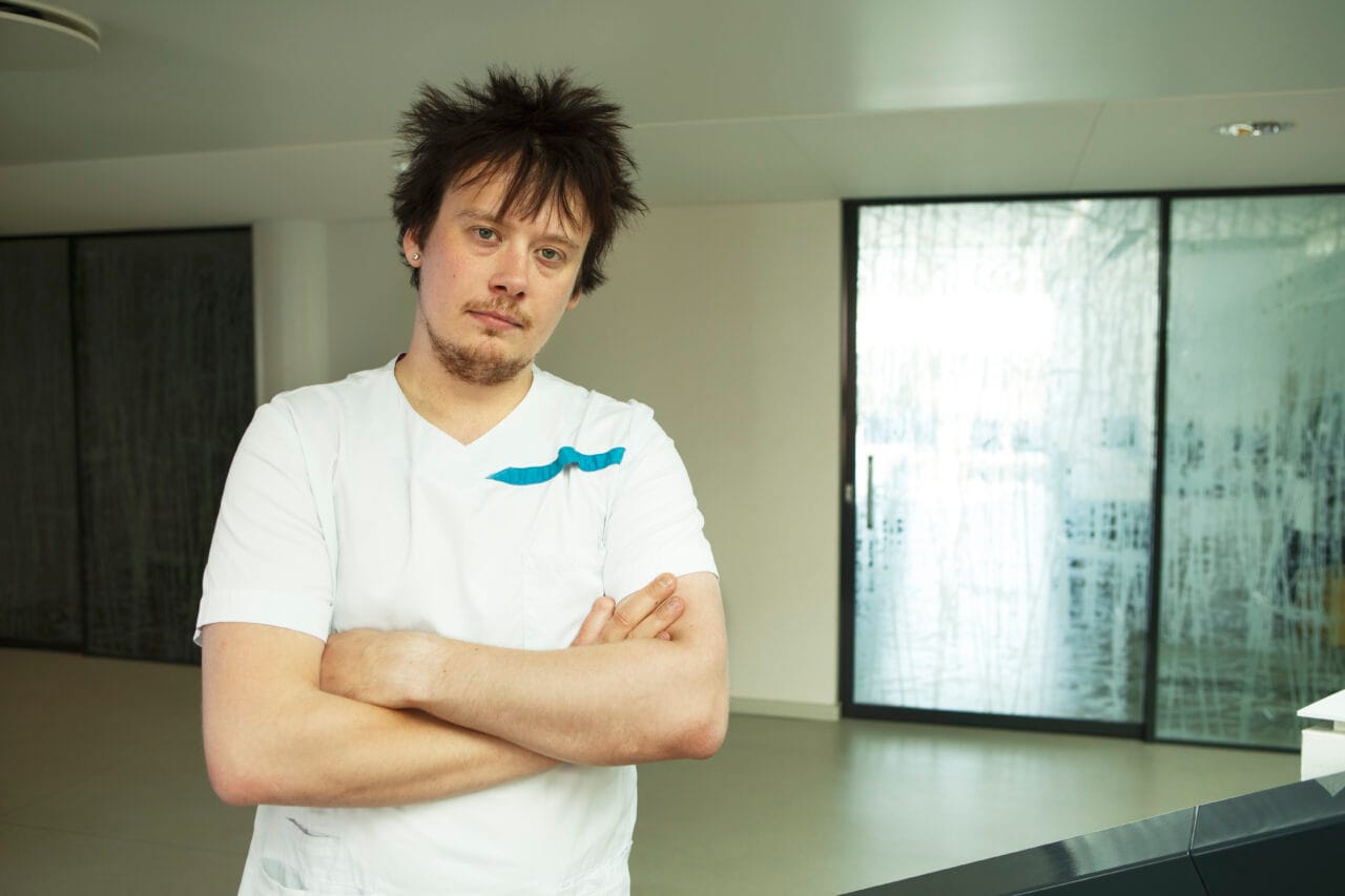 Henkilö seisoo sisätilassa valkoisessa työasussa