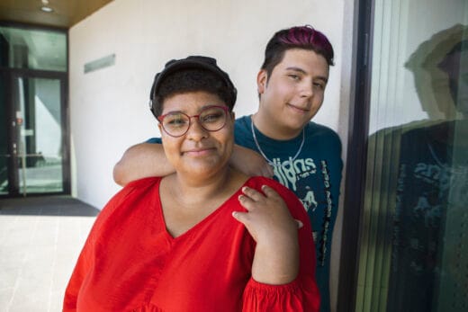 Tyttö ja poika hymyilevät kampuksen pihalla.