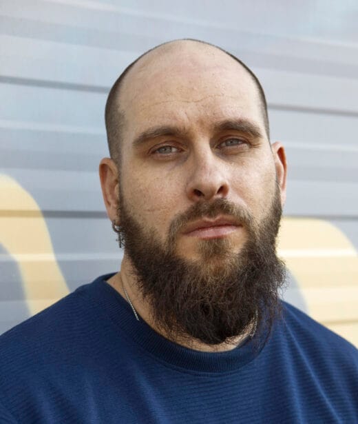 Mies katsoo suoraan kameraan muotokuvassa.