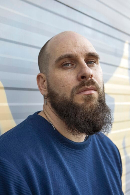 Mies katsoo suoraan kameraan muotokuvassa.