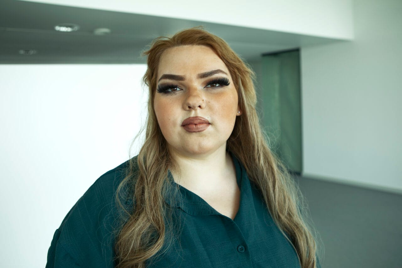 Nainen seisoo käytävällä ja katsoo kameraan.