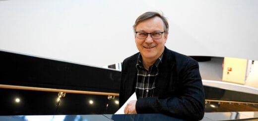 kasvokuva Jouko Porkastapuolivartalokuva Jouko Porkasta istumassa pöydän äärellä isojen ikkunoiden vieressäkäsi joka pitelee pientä puukehyksissä olevaa metallikaiverrustaJouko Porkan kasvokuva