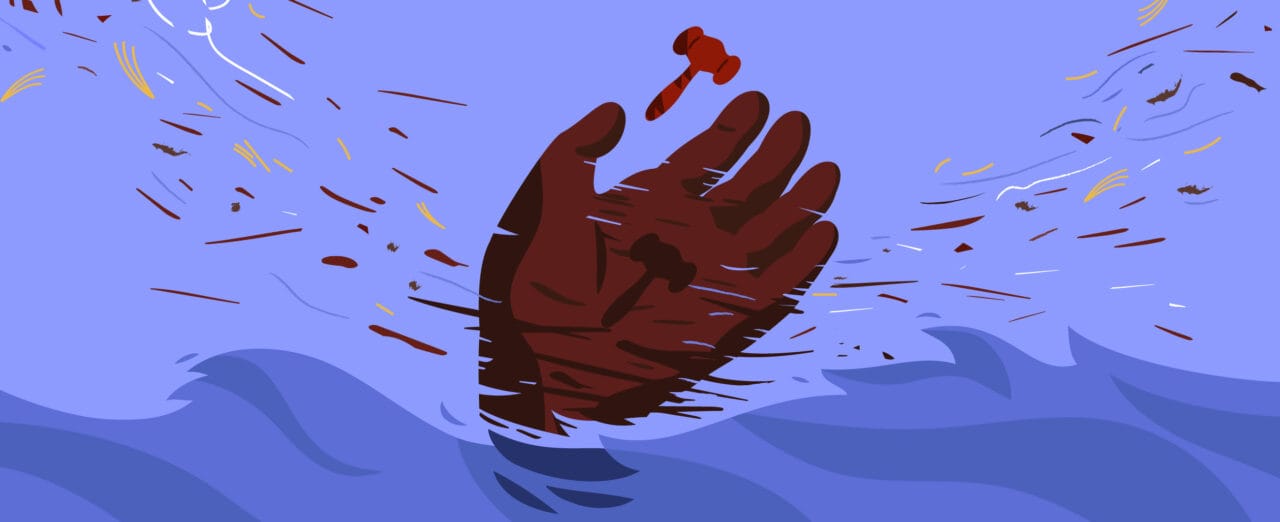 Kuvassa käsi kurkottelee oikeuden nuijaa tuulisessa säässä